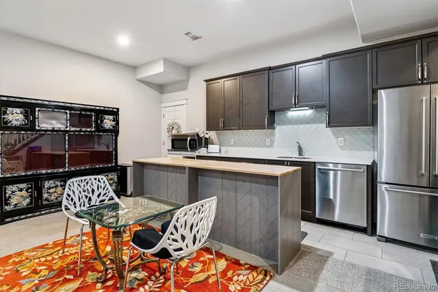 a outdoor kitchen with stainless steel appliances kitchen island granite countertop a refrigerator and a stove