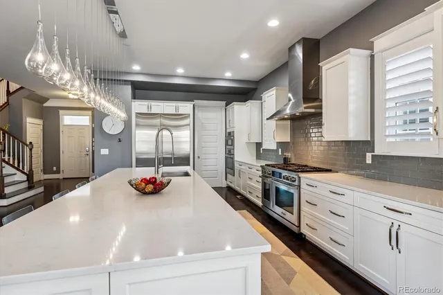 a kitchen with stainless steel appliances granite countertop a stove a sink a refrigerator and a dining table with wooden floor