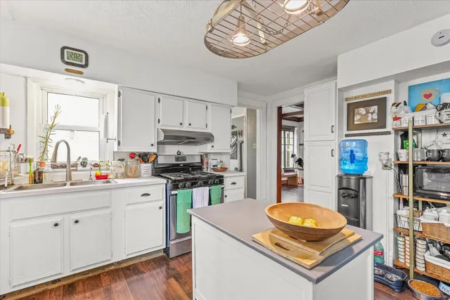 a kitchen with stainless steel appliances a stove a sink a refrigerator cabinets and a window