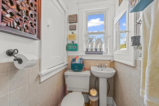 a bathroom with a sink mirror toilet and next to a window