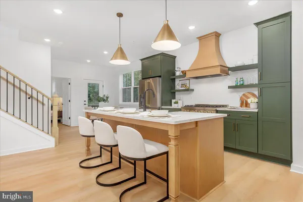 a kitchen with stainless steel appliances granite countertop a sink a stove a refrigerator and island with wooden floor
