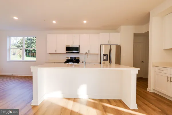 a view of kitchen with stainless steel appliances granite countertop a refrigerator a stove a sink and a microwave with wooden floor