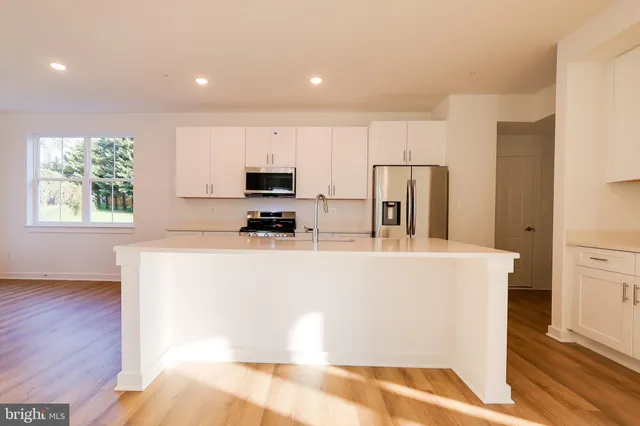 a view of kitchen with stainless steel appliances granite countertop a refrigerator a stove a sink and a microwave with wooden floor