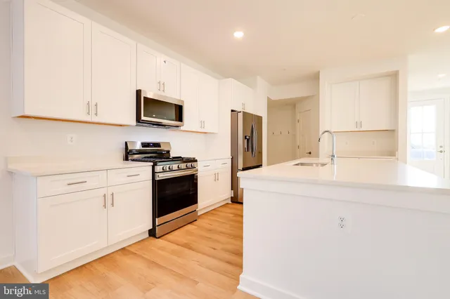a kitchen with stainless steel appliances a refrigerator sink and white cabinets
