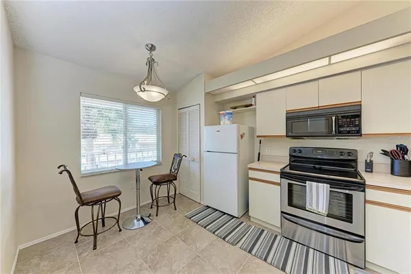 a kitchen with stainless steel appliances granite countertop a stove top oven a sink dishwasher a dining table and chairs with wooden floor