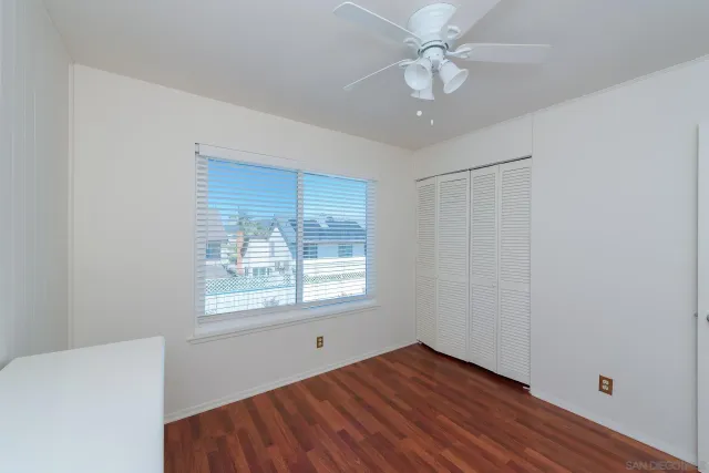 a view of an empty room with window and wooden floor