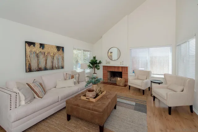a living room with furniture a rug a fireplace and a large window