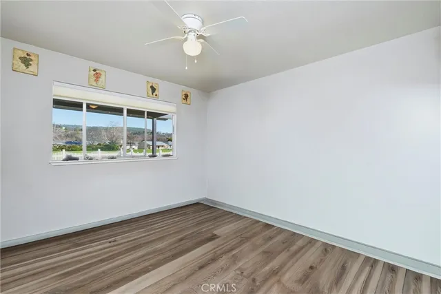 an empty room with wooden floor and ceiling fan