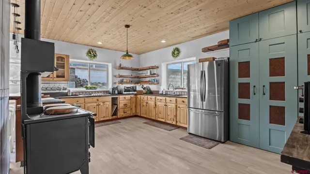 a kitchen with stainless steel appliances granite countertop a stove a sink dishwasher and white cabinets with wooden floor