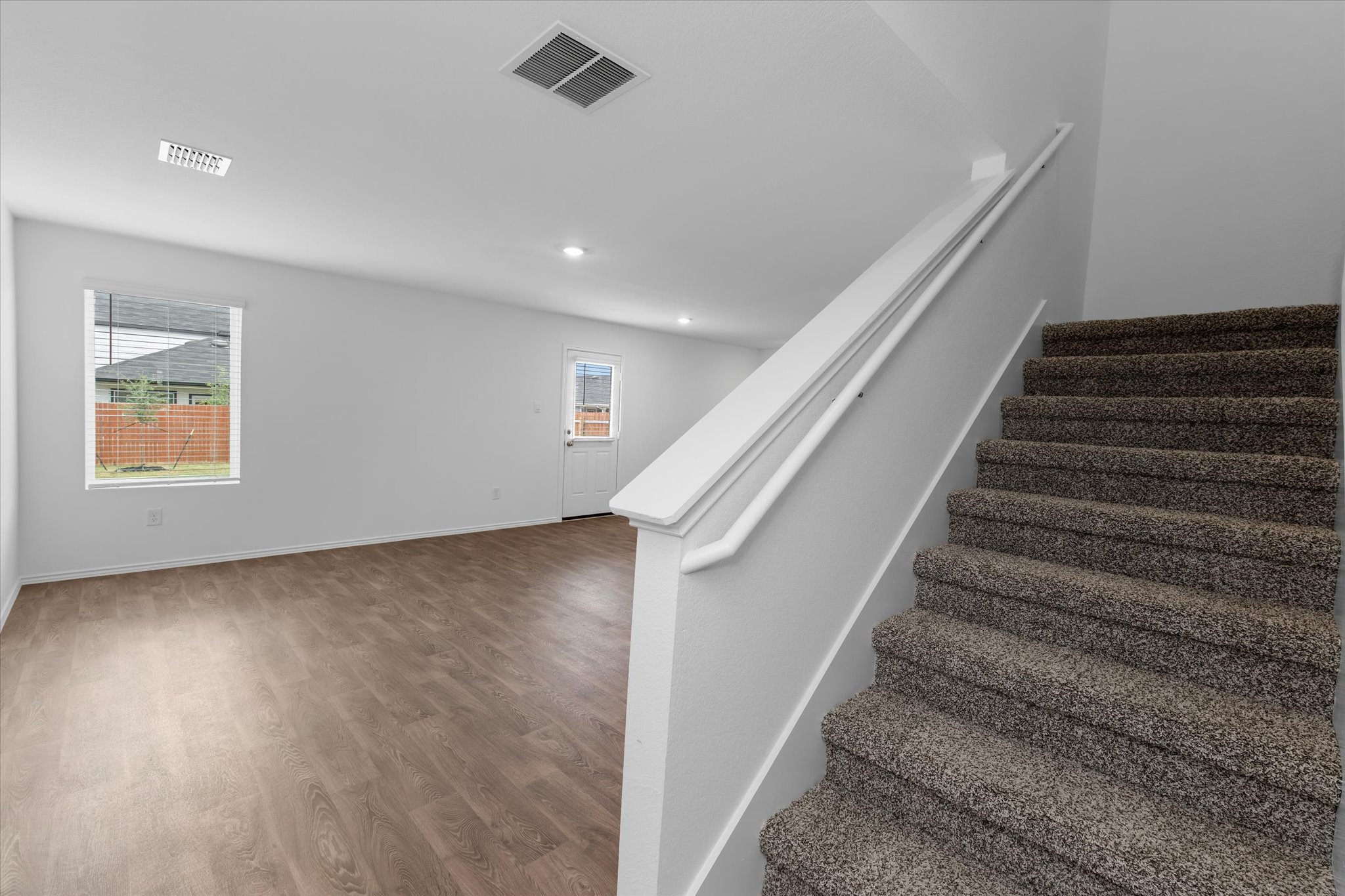 456 Sandringham Loop Kyle, TX 78640 - Photo 25 of 40 A well-lit interior offers a harmonious blend of durable wood-look flooring and plush carpeting leading to the upper level.