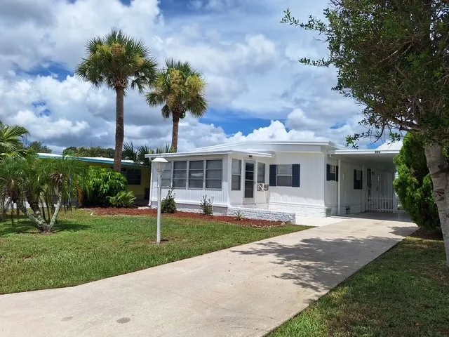 a front view of a house with garden and trees