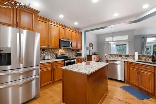 a kitchen with a refrigerator a sink and a stove top oven with wooden floor