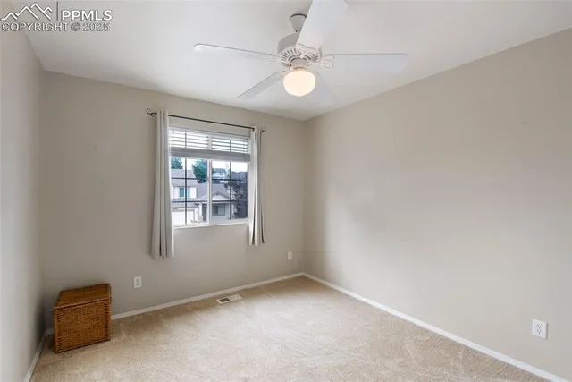 an empty room with windows and ceiling fan
