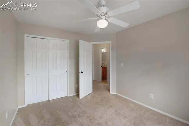 a view of a room with a ceiling fan and carpet