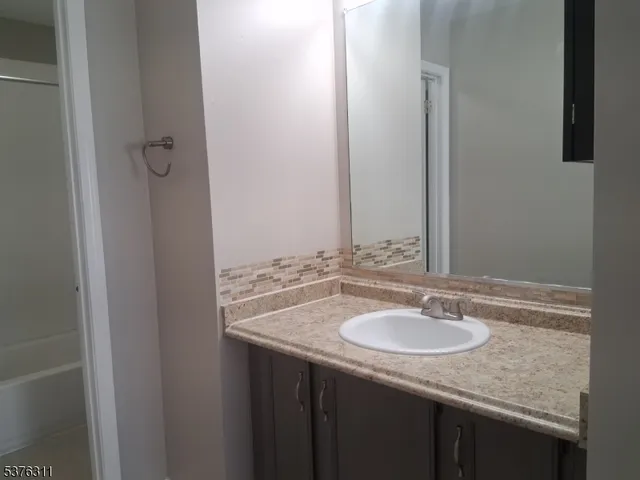 a bathroom with a granite countertop sink and a mirror