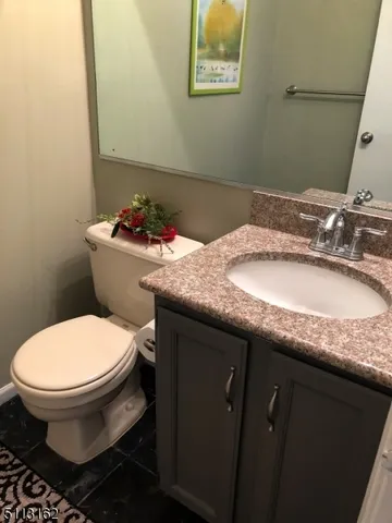 a bathroom with a granite countertop toilet sink and mirror
