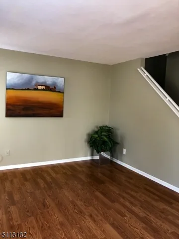 a view of an empty room with wooden floor and closet