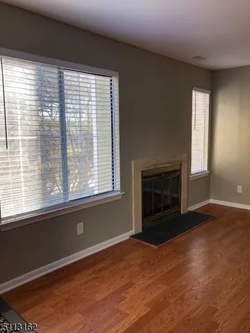 a view of empty room with wooden floor and fireplace