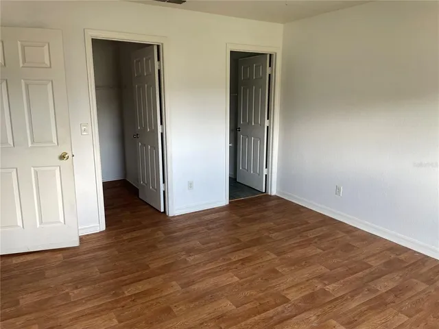 an empty room with wooden floor and closet area