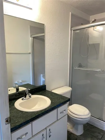 a bathroom with a granite countertop sink toilet and a mirror