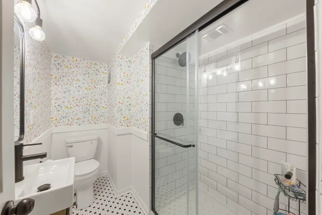 a bathroom with a toilet a sink a shower and a mirror