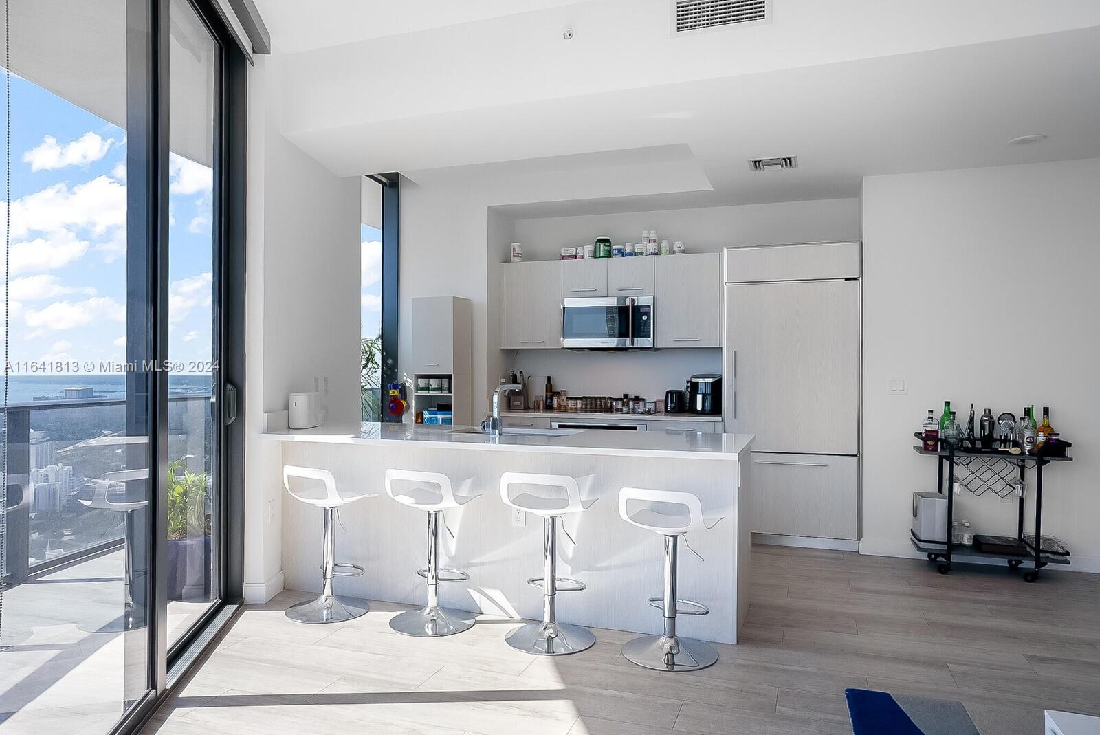 45 Southwest 9th Street, Unit 4403 Miami, FL 33130 - Photo 5 of 21 a white kitchen with wooden floor and stainless steel appliances