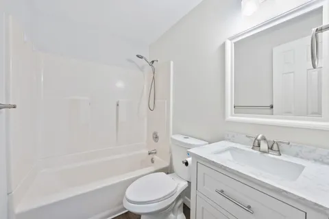 a bathroom with a granite countertop toilet a sink and a bathtub
