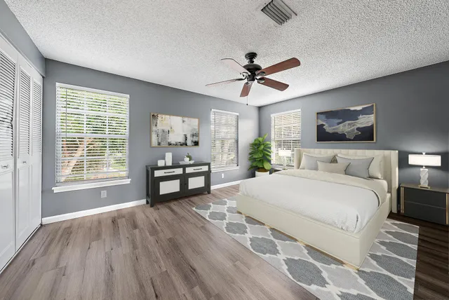 a spacious bedroom with a bed a dresser and wooden floor