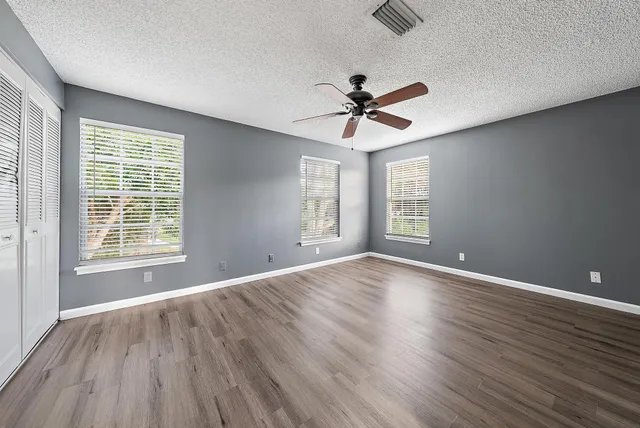 a view of empty room with wooden floor and fan