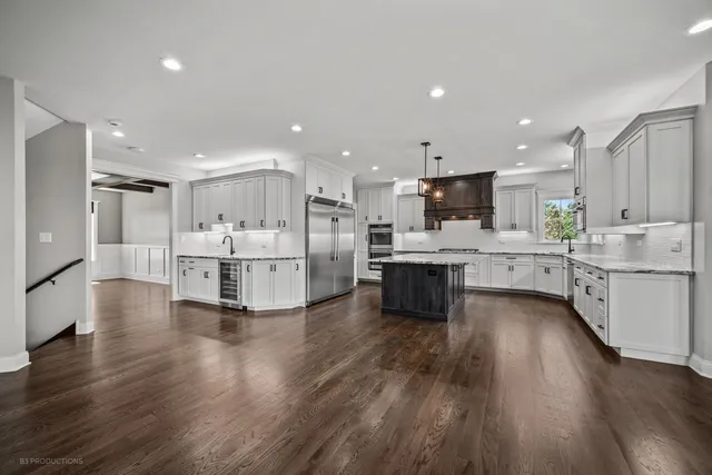 a large white kitchen with a center island stainless steel appliances and a cabinets