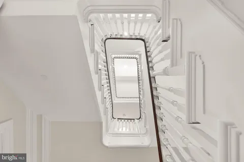 a view of an empty room with wooden floor and fan