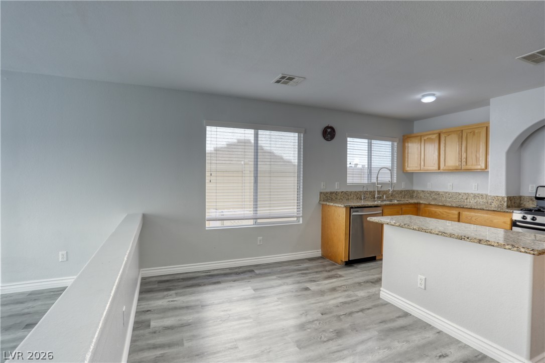7226 Cestrum Road Las Vegas, NV 89113 - Photo 11 of 28 Kitchen with light stone countertops, light wood finished floors, stainless steel appliances, light wood finish cabinets, and a center island