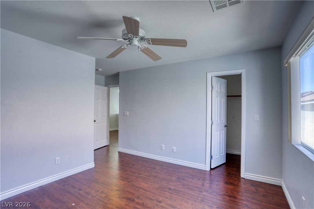 7226 Cestrum Road Las Vegas, NV 89113 - Photo 17 of 28 Unfurnished bedroom featuring dark wood finished floors, a spacious closet, and ceiling fan