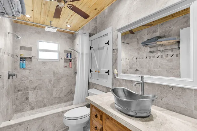 a bathroom with a granite countertop sink a toilet a mirror and shower