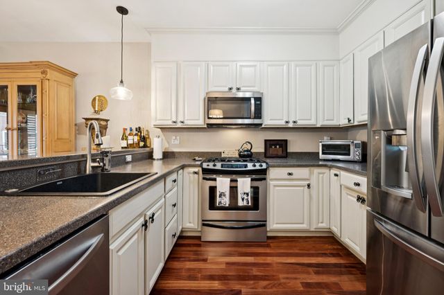 a kitchen with stainless steel appliances granite countertop a sink a stove and a refrigerator