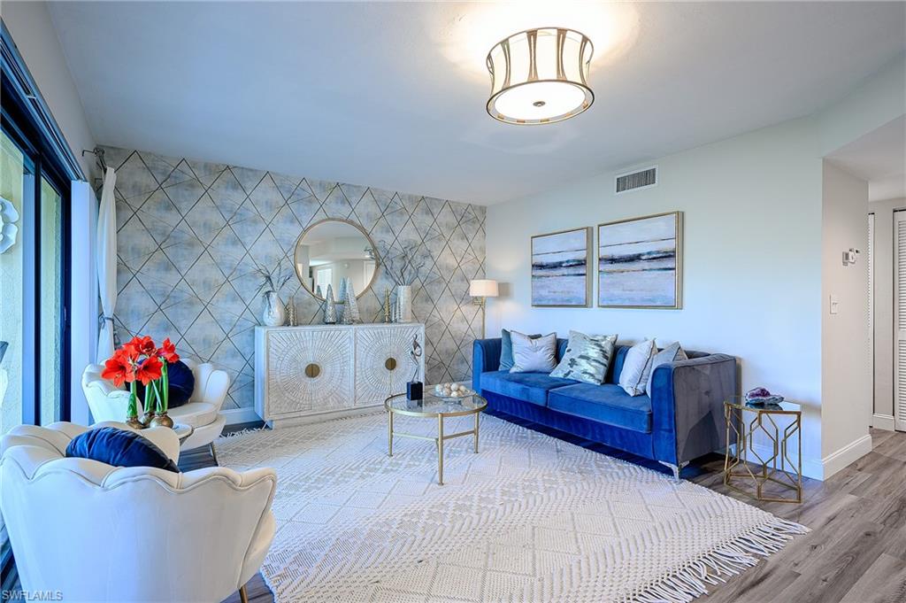 586 Beachwalk Circle, Unit O205 Naples, FL 34108 - Photo 13 of 36 a living room with furniture a rug and a chandelier
