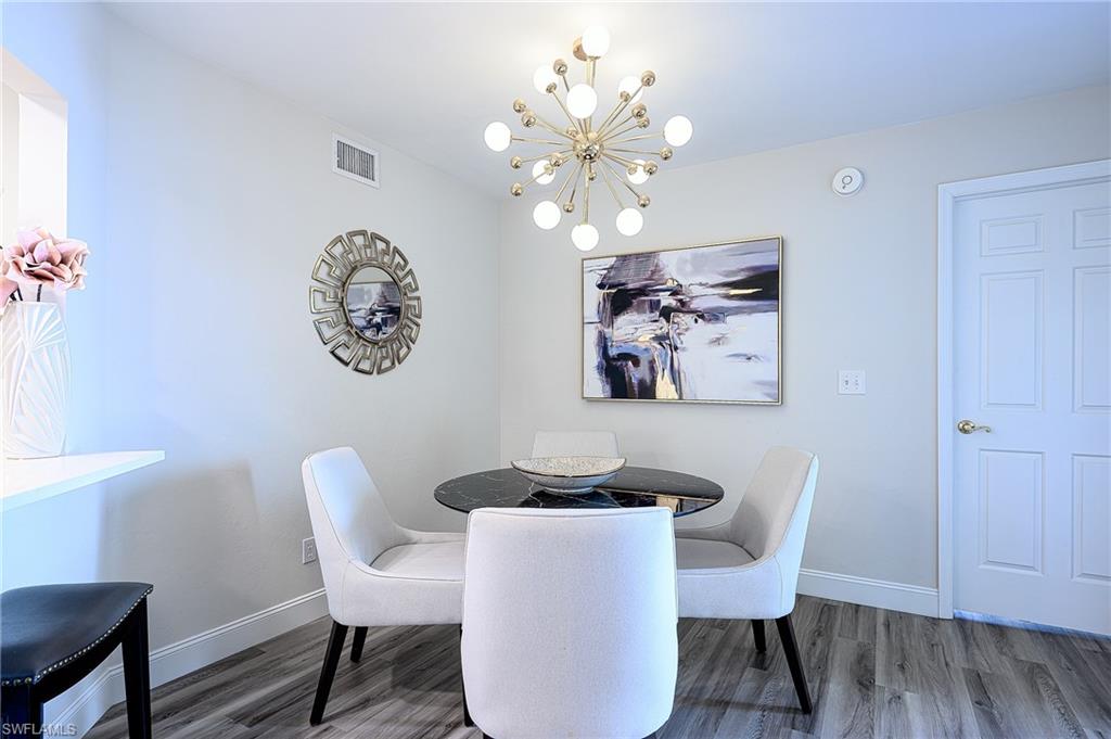 586 Beachwalk Circle, Unit O205 Naples, FL 34108 - Photo 15 of 36 a dining room with furniture and a chandelier