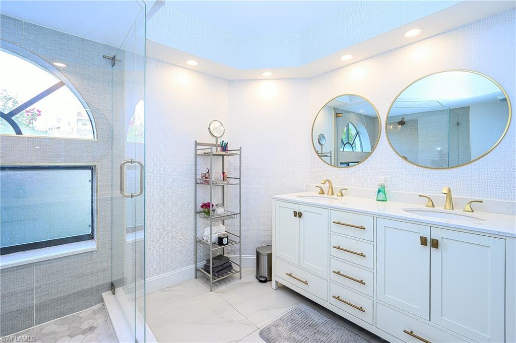 586 Beachwalk Circle, Unit O205 Naples, FL 34108 - Photo 18 of 36 a room with two mirror and a clock on the wall