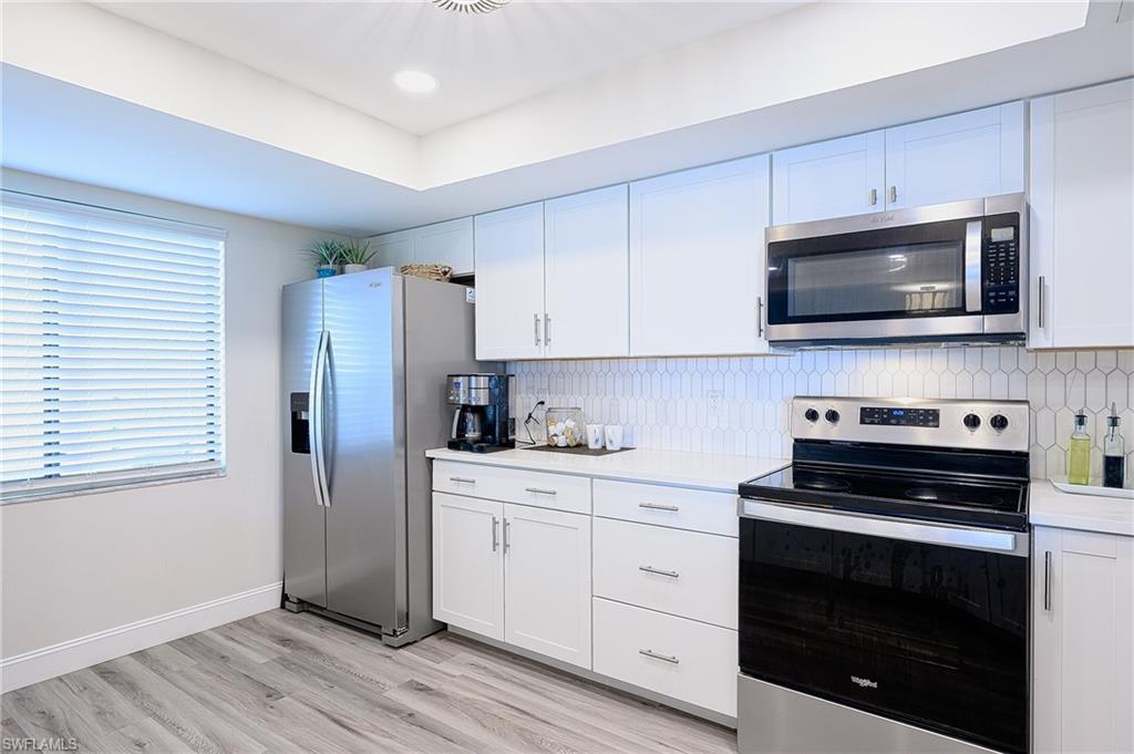 586 Beachwalk Circle, Unit O205 Naples, FL 34108 - Photo 5 of 36 a kitchen with stainless steel appliances a stove microwave and sink
