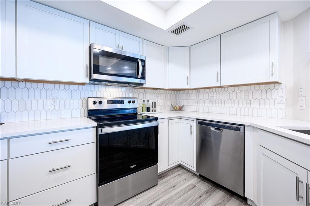 586 Beachwalk Circle, Unit O205 Naples, FL 34108 - Photo 7 of 36 a kitchen with a stove and a microwave
