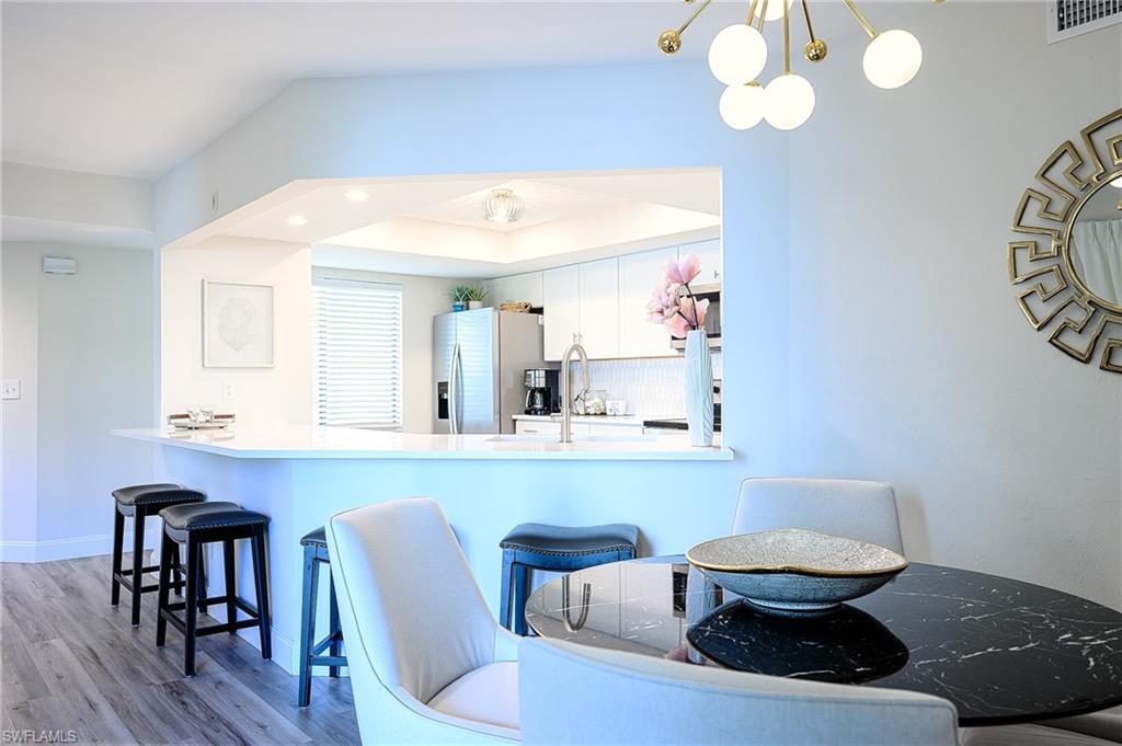 586 Beachwalk Circle, Unit O205 Naples, FL 34108 - Photo 10 of 36 a kitchen with a table and chairs in it