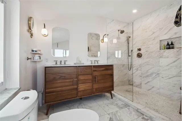 a bathroom with a granite countertop sink a toilet a mirror and shower