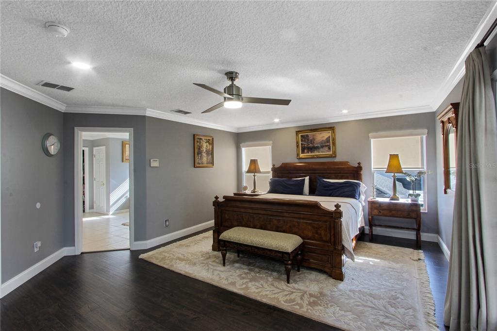5536 Ansley Way Mount Dora, FL 32757 - Photo 21 of 49 a spacious bedroom with a bed a chandelier and a dresser