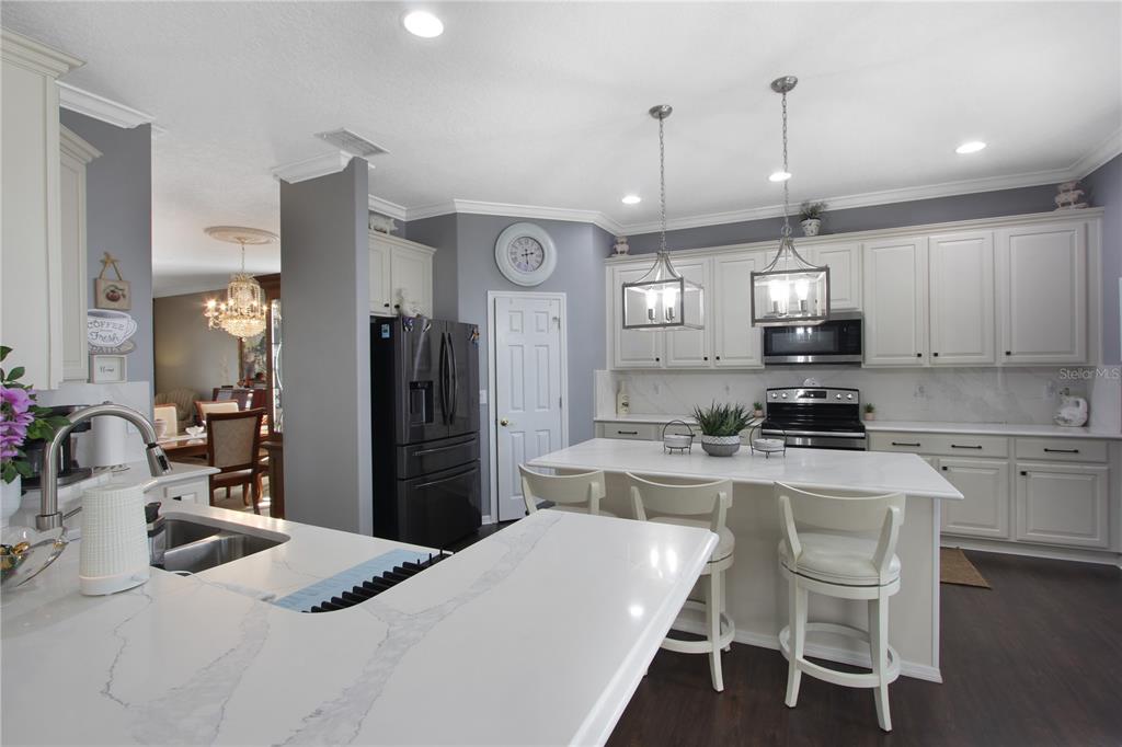 5536 Ansley Way Mount Dora, FL 32757 - Photo 33 of 49 a kitchen with a refrigerator a stove a sink a dining table and chairs