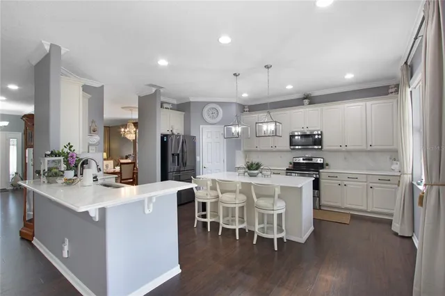 a kitchen with stainless steel appliances kitchen island granite countertop a sink a stove a refrigerator cabinets and chairs