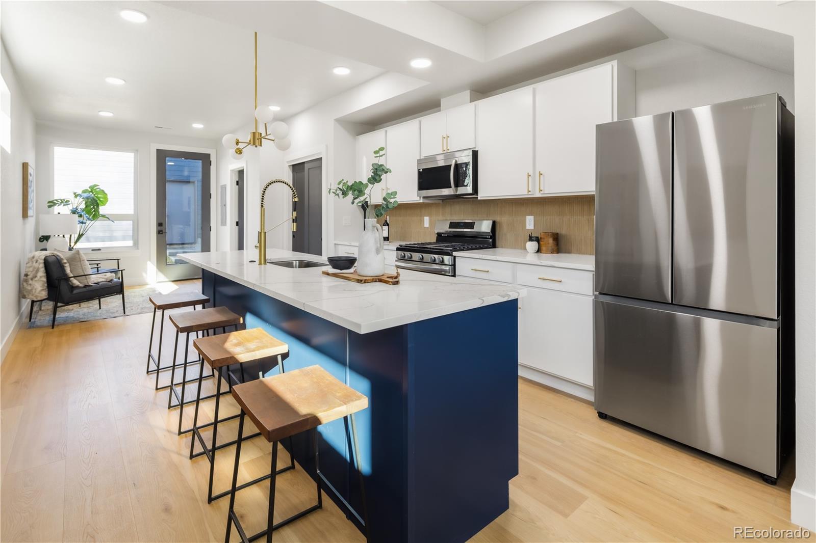 a kitchen with stainless steel appliances a refrigerator a stove a sink dishwasher and white cabinets with wooden floor