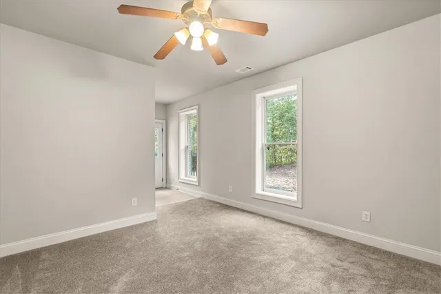 en empty room with windows and chandelier fan