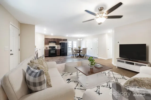 a living room with furniture and a flat screen tv with kitchen view