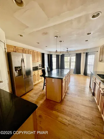 a large kitchen with stainless steel appliances kitchen island granite countertop a large counter top and wooden floors