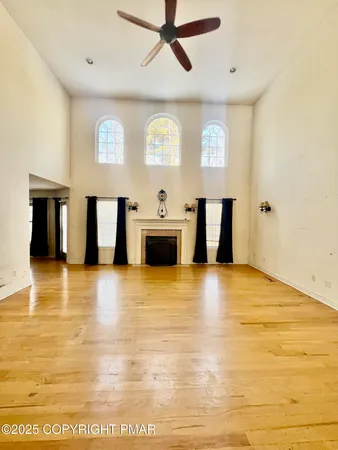 a view of an empty room with window and wooden floor